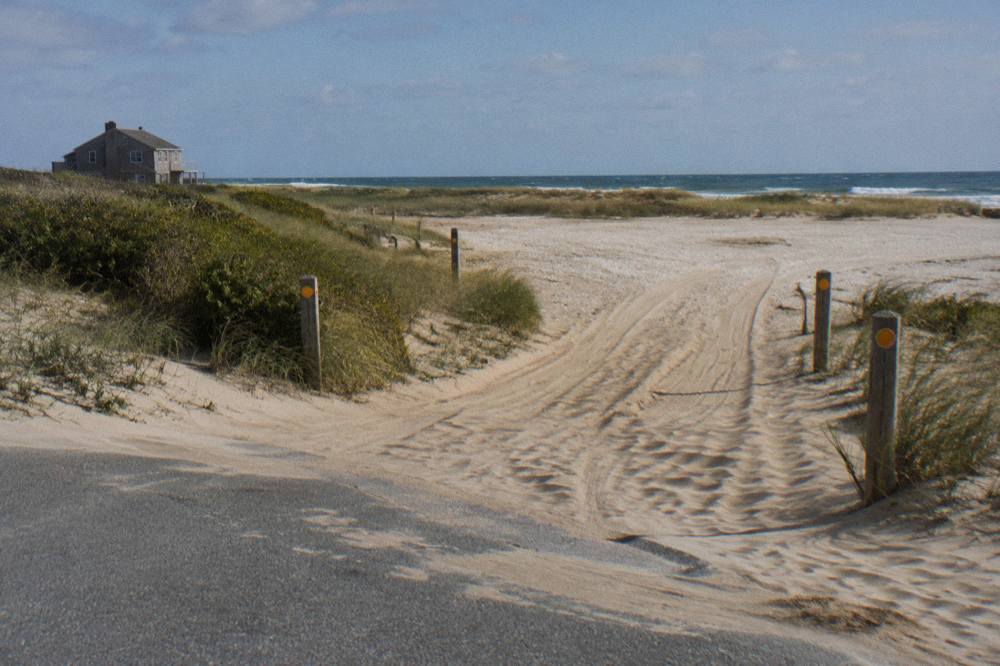Open wet sand with tire tracks, dunes and gulls where the beach becomes a driving route