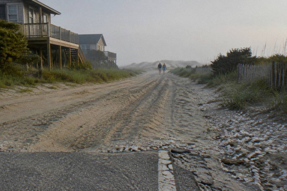 Open sand beach with tire tracks stretching toward distant dunes