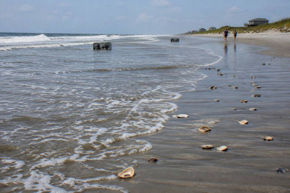 Ocean waves washing high onto a wide sand beach at rising tide