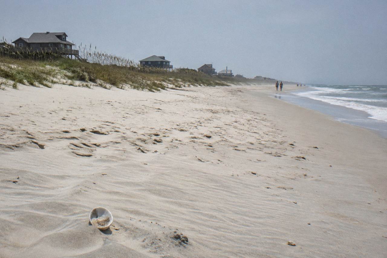Wide empty beach at the northern end of Corolla with dune grass and low surf