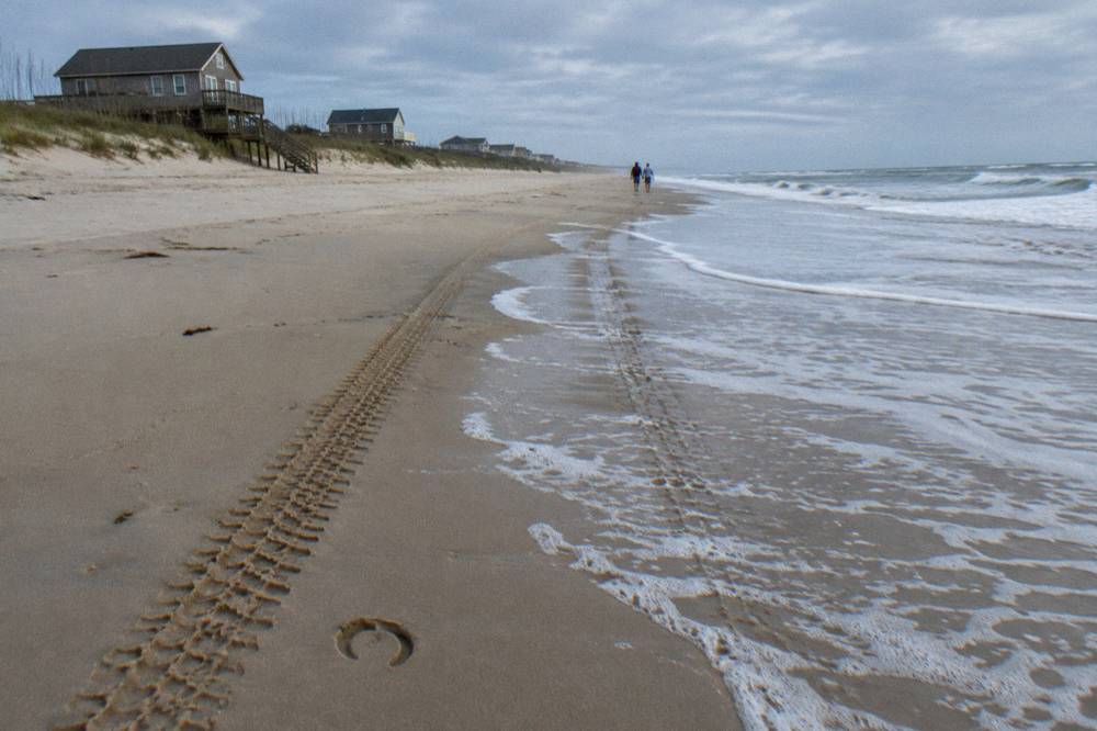 Tire tracks in firm wet sand at the waterline of the Corolla four wheel drive beach