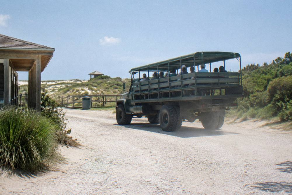 Open air four wheel drive tour truck parked on the beach with passengers in seats