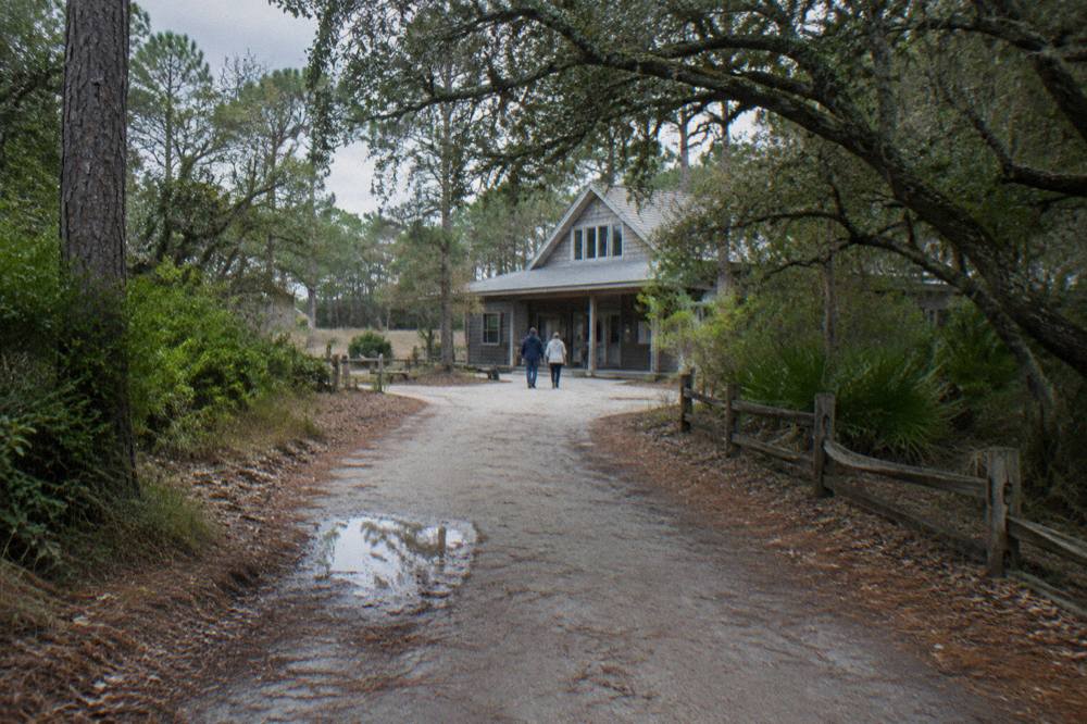 Wooded dirt road leading toward a small Outer Banks museum building