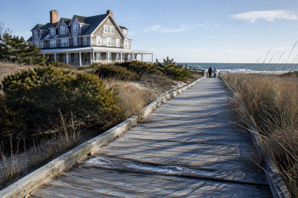 Weathered wooden walkway crossing dunes toward a wide Atlantic beach