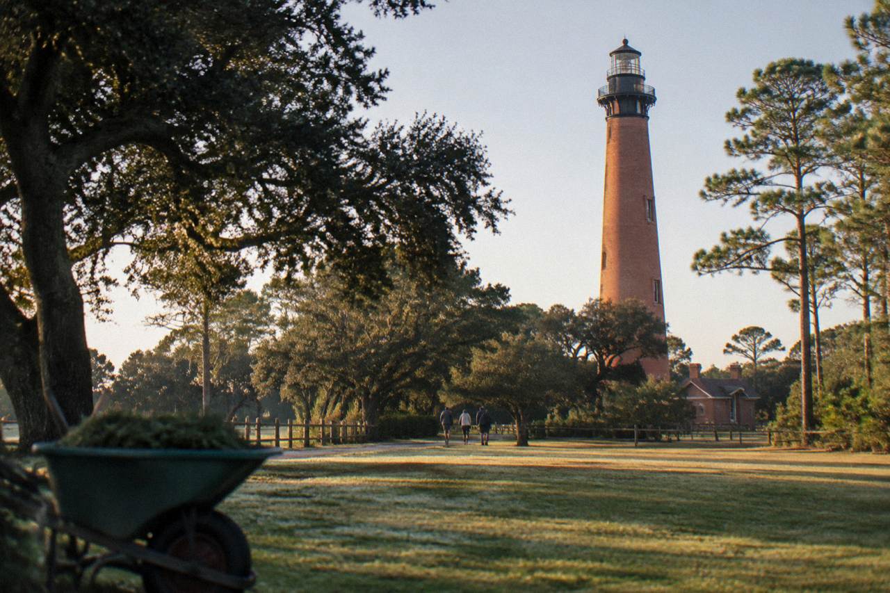 Red brick lighthouse tower above maritime forest at the northern end of the Outer Banks