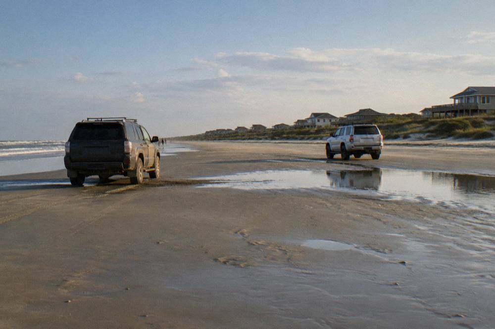 Four-wheel-drive vehicles parked on the wide hard-packed sand of the off-road beach