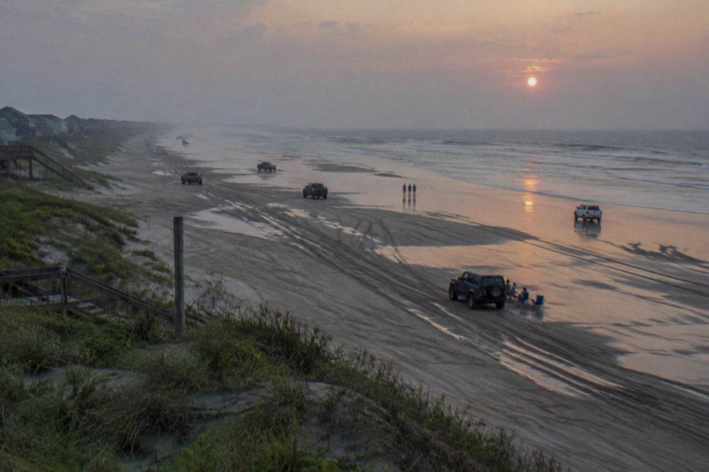 Off-road vehicles spread along a wide northern Outer Banks beach at low tide